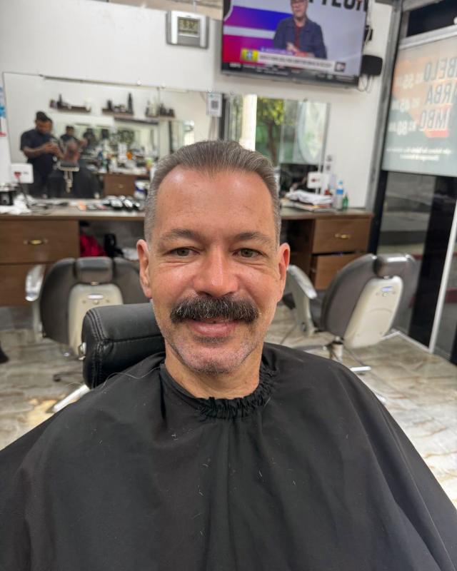 Cliente de bigode sorrindo depois do corte